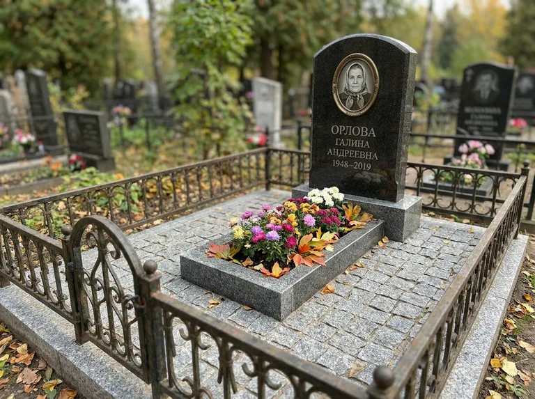 Благоустроенное захоронение с гранитной плиткой, оградой и цветником в Ханты-Мансийске
