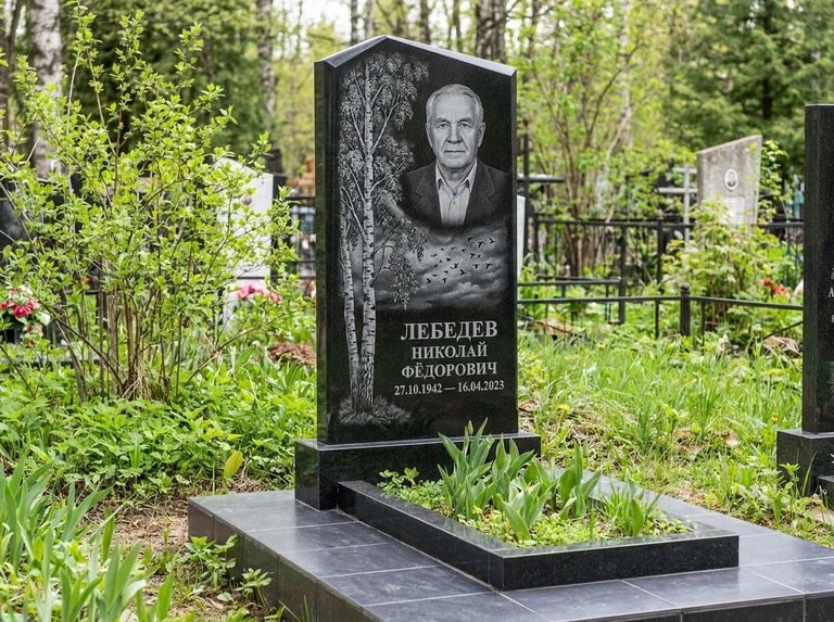 Памятник с гравировкой берёзы: вертикальная стела со скошенным верхом — берёза и стая птиц в небе, гранитный цоколь с тёмной плиткой, работа «Лебедев» в Ханты-Мансийске