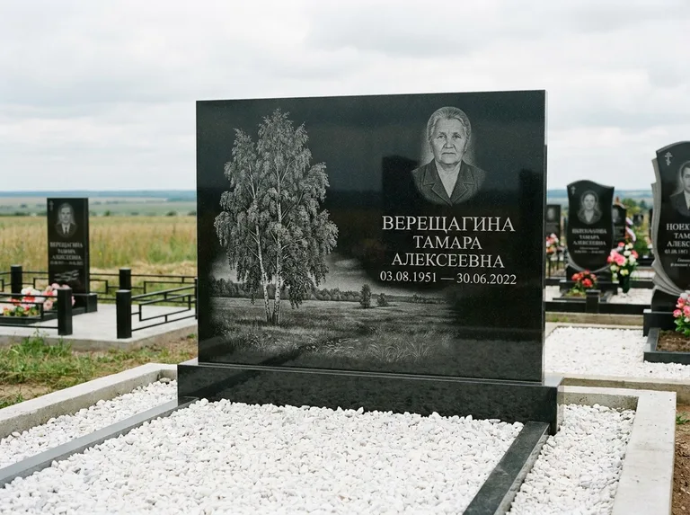 Памятник с гравировкой берёзы: широкая горизонтальная стела — берёза у поля, простор до горизонта, белая мраморная крошка с бордюром, работа «Верещагина» в Ханты-Мансийске