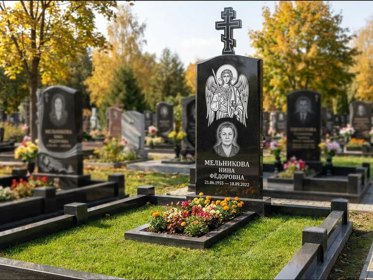 Памятник с гравировкой иконы: округлая стела-медальон с ликом — гравировка Богородицы «Семистрельная», луговые травы и полевые цветы за участком, работа «Гущин» в Ханты-Мансийске