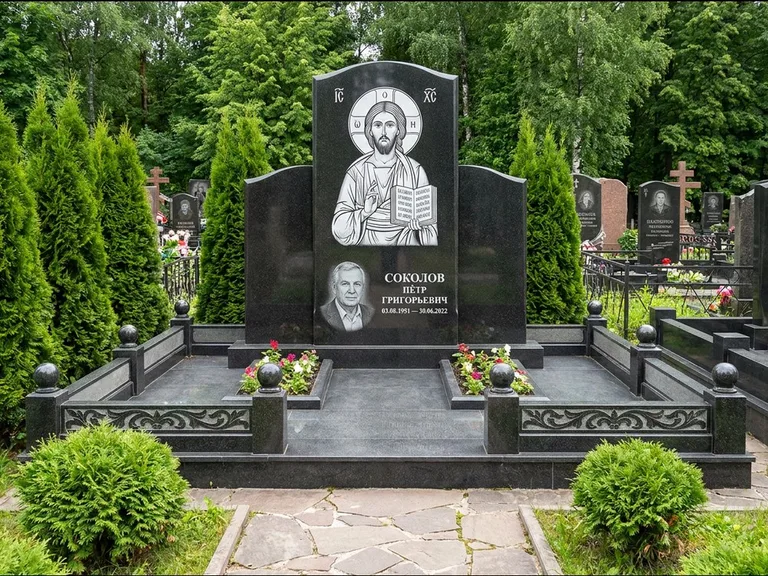 Памятник с гравировкой иконы: широкая горизонтальная лежачая плита-стела — икона в резной рамке-киоте, серая гравийная отсыпка с бордюром, работа «Богданова» в Ханты-Мансийске