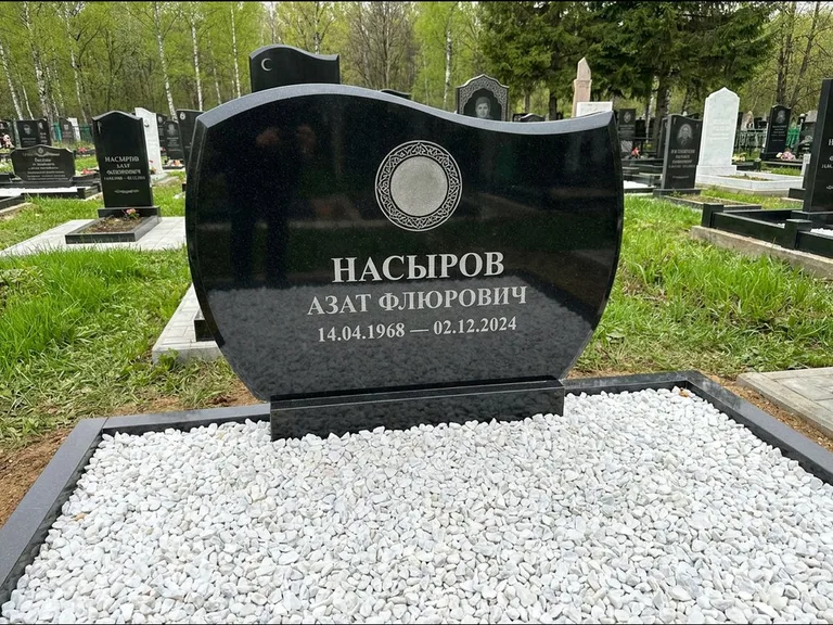 Мусульманский памятник: стела с волнообразным скошенным верхом — гравировка мечети под полумесяцем и звёздами, белая мраморная крошка с бордюром, работа «Насыров» в Ханты-Мансийске