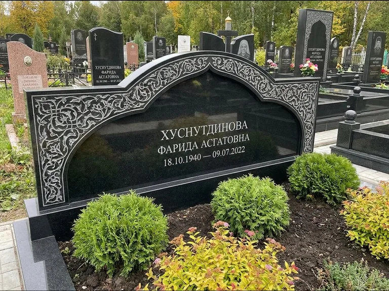 Мусульманский памятник: вытянутая горизонтальная семейная стела с аркой — белая гравировка силуэта мечети с минаретами, участок с декоративными кустами, работа «Зарипова» в Ханты-Мансийске