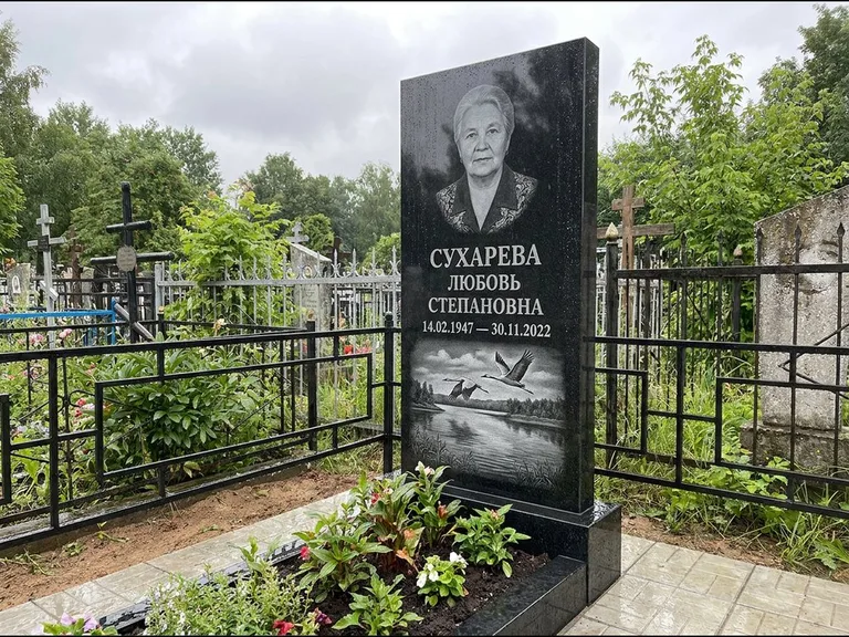 Памятник с гравировкой журавлей — гравировка пары журавлей над гладью озера в нижней части, работа «Сухарева» в Ханты-Мансийске