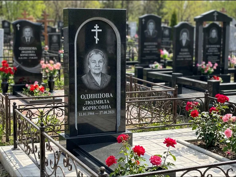 Памятник из чёрного гранита — скромная невысокая стела с крестом с терновым венцом, работа «Лаврентьева» в Ханты-Мансийске