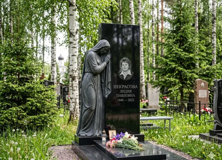 Гранитная фигура скорбящего мужчины у чёрной стелы в Ханты-Мансийске